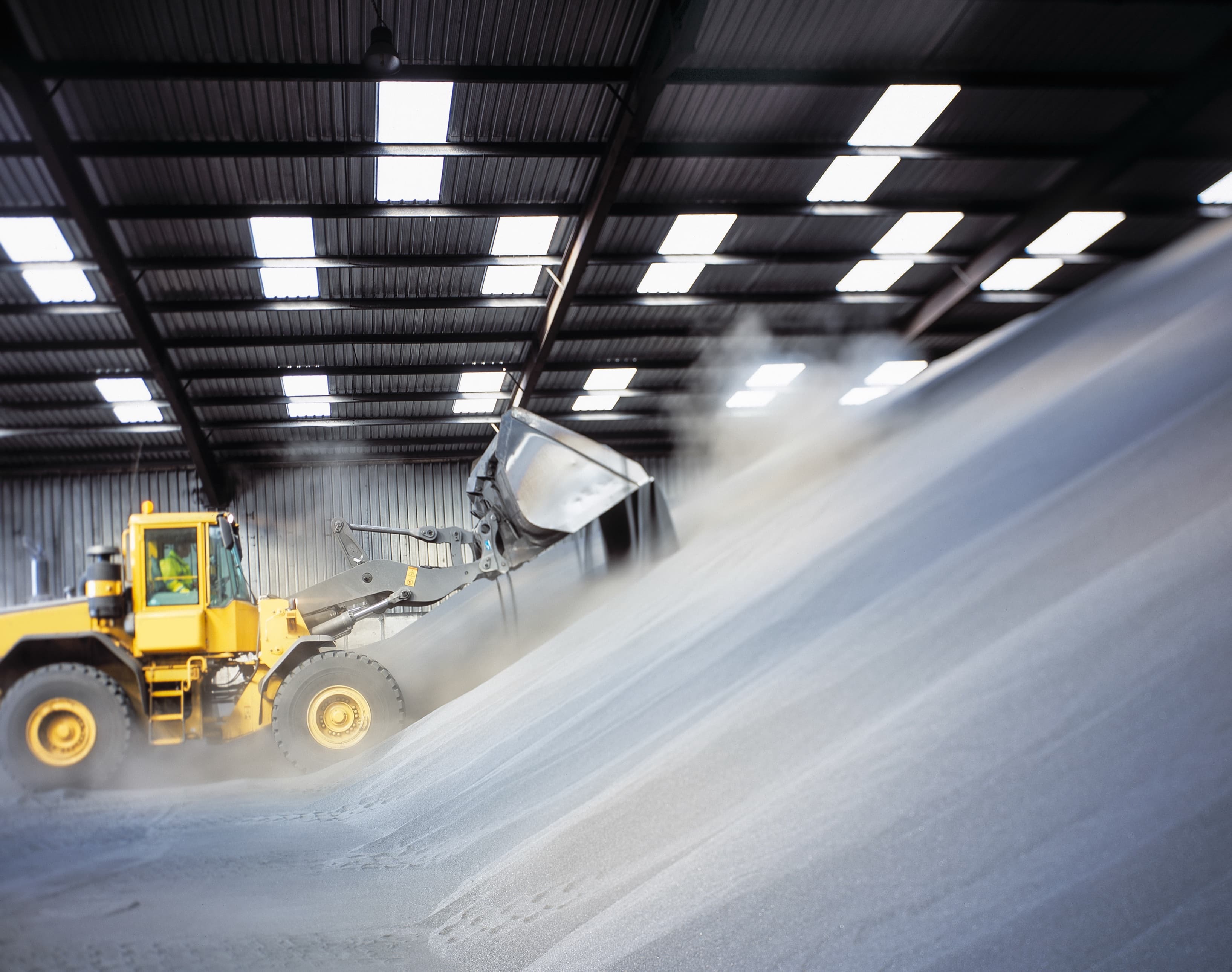 Front loader working a bulk material pile inside a storage shed