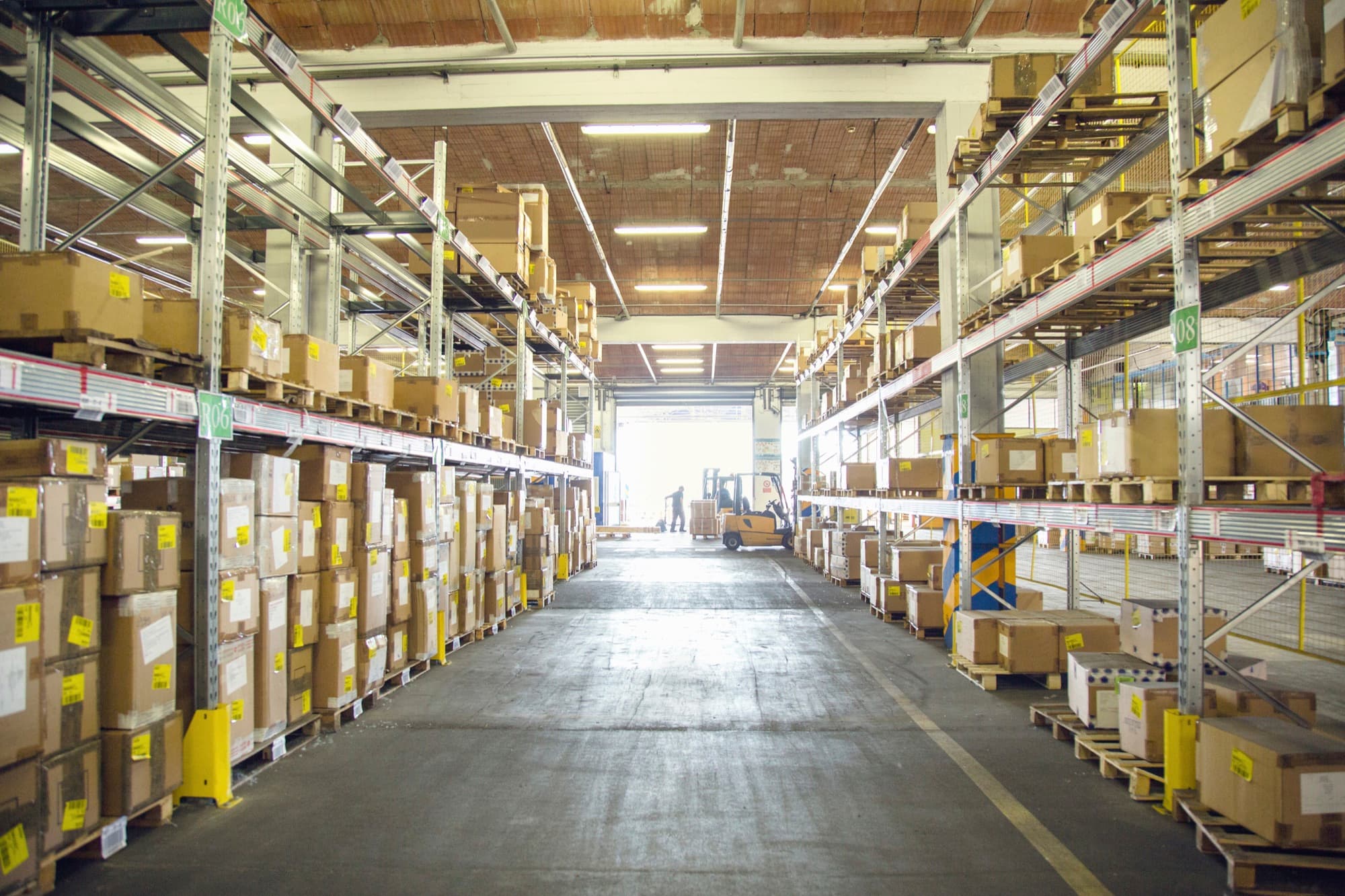 Forklift drivers moving palletized freight in a distribution warehouse