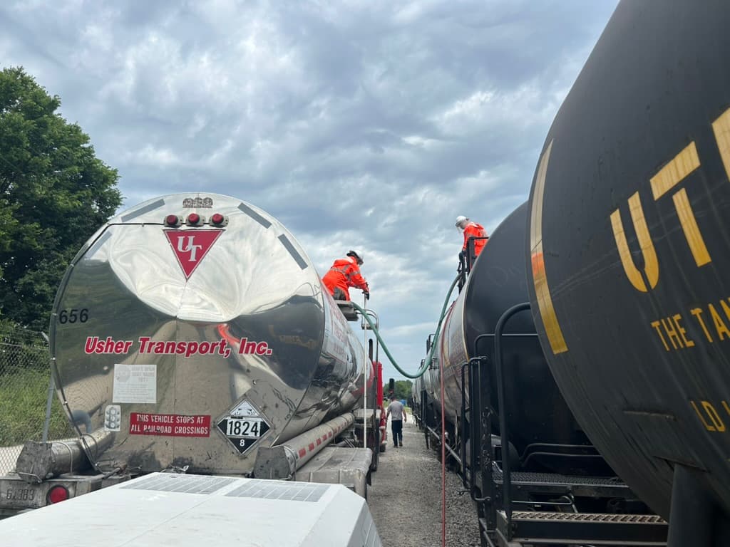 Usher Transport crew transloading product between railcars and a tank trailer